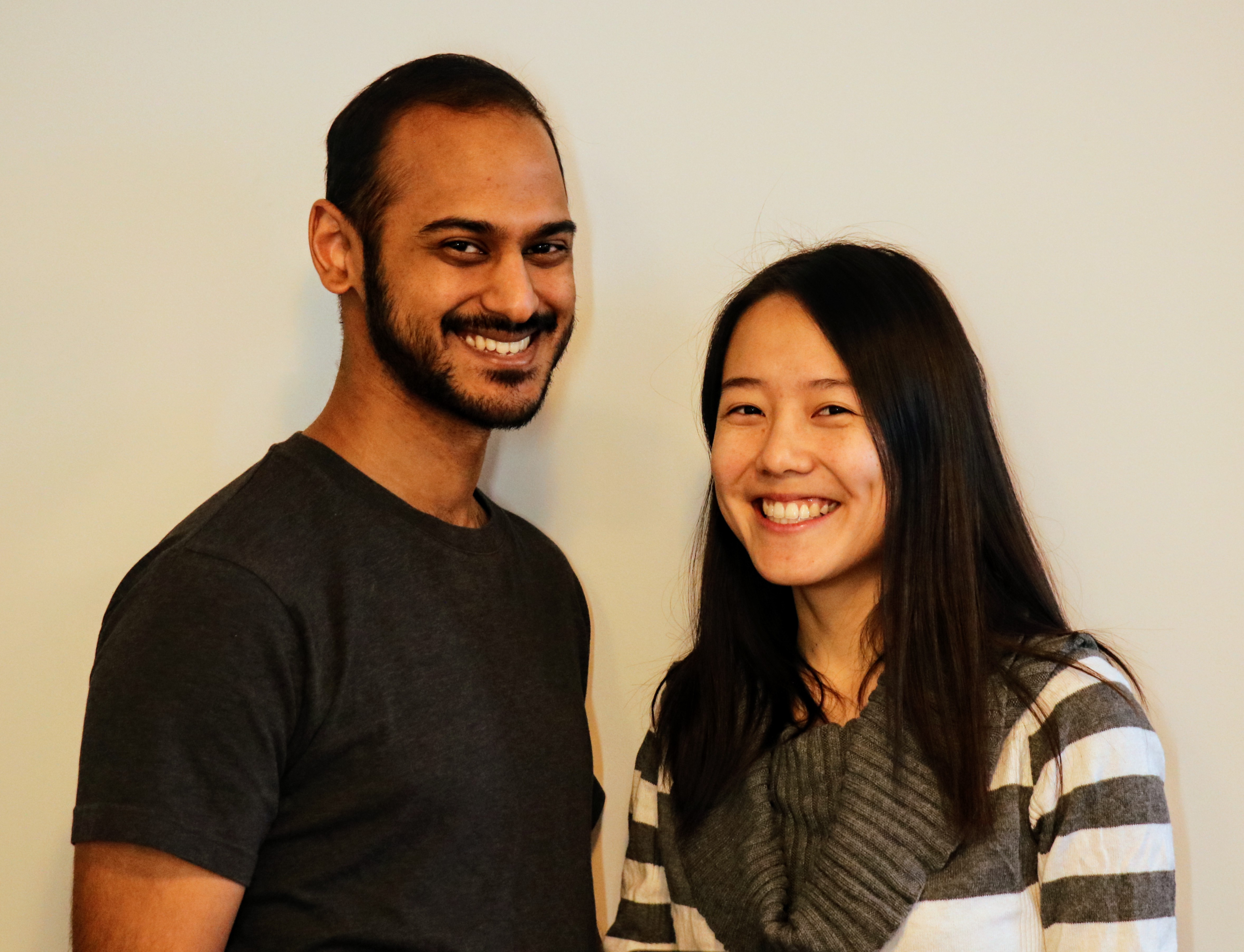 Alvin and Anita, in front of wall, smiling awkwardly at camera.